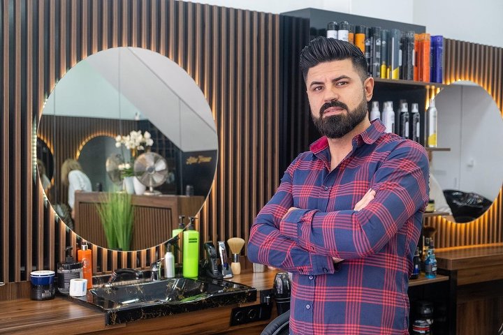 Stylist mit Bart vor dem Rundspiegel